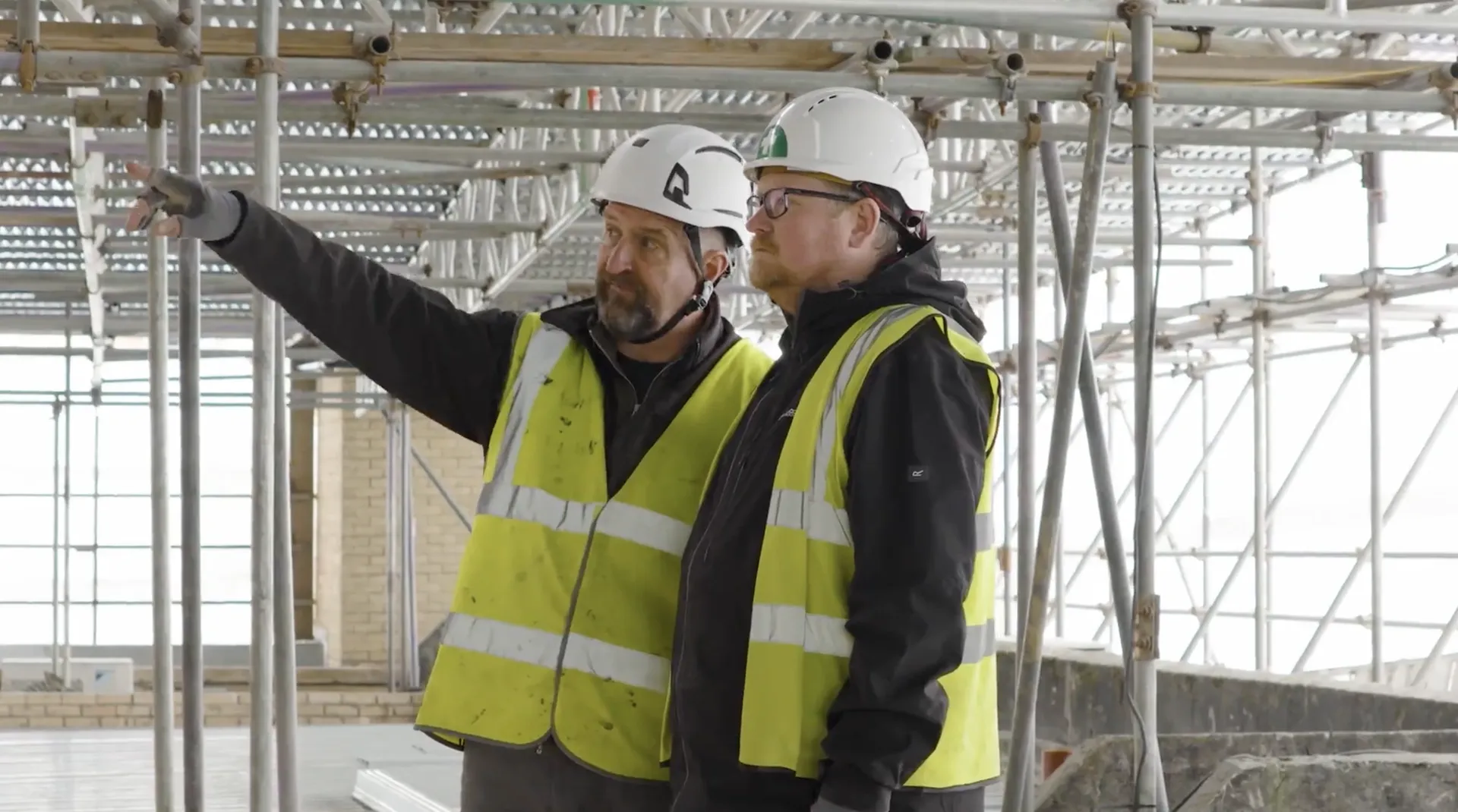 Two members of the JPS team in hard hats talking through the works beneath the temporary roof at St David's, Cardiff